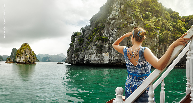 Photo of a girl standing on a boat and enjoying the view of Ha Long Bay