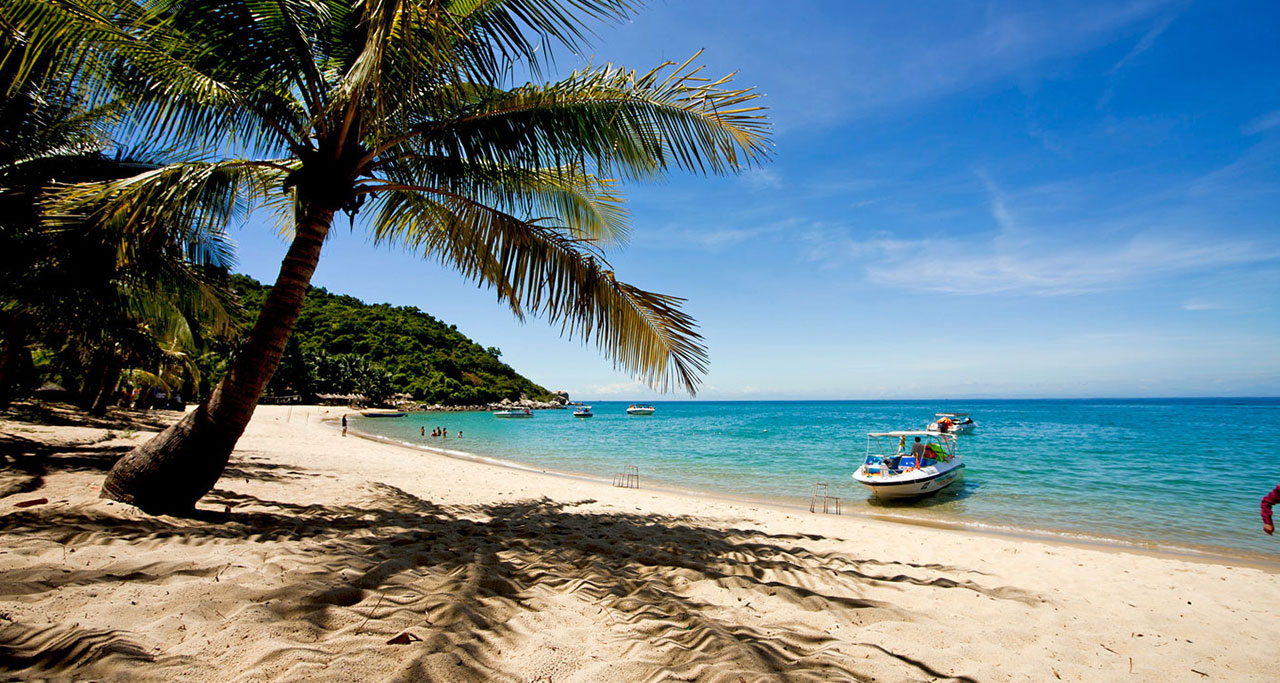 Coconut trees, speedboats and blue water at Cu Lao Cham, Hoi An