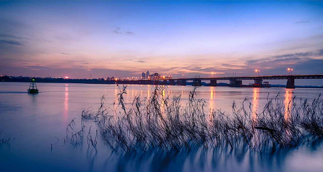 Tranquil Hanoi's Red River and Long Bien Bridge at sunset