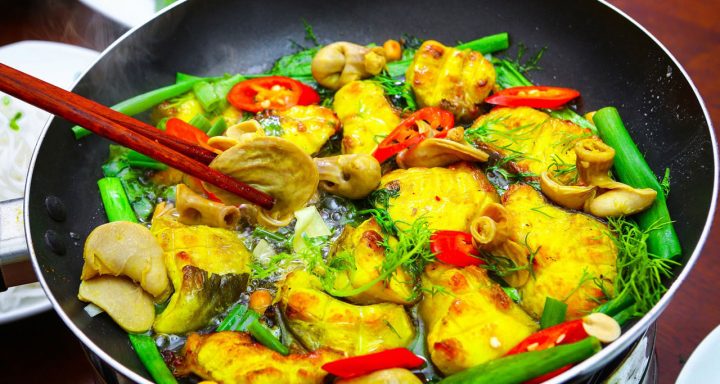 Cha Ca La Vong, a dish of turmeric-marinated white fish cooked on a grill and served with fresh rice noodles and herbs.