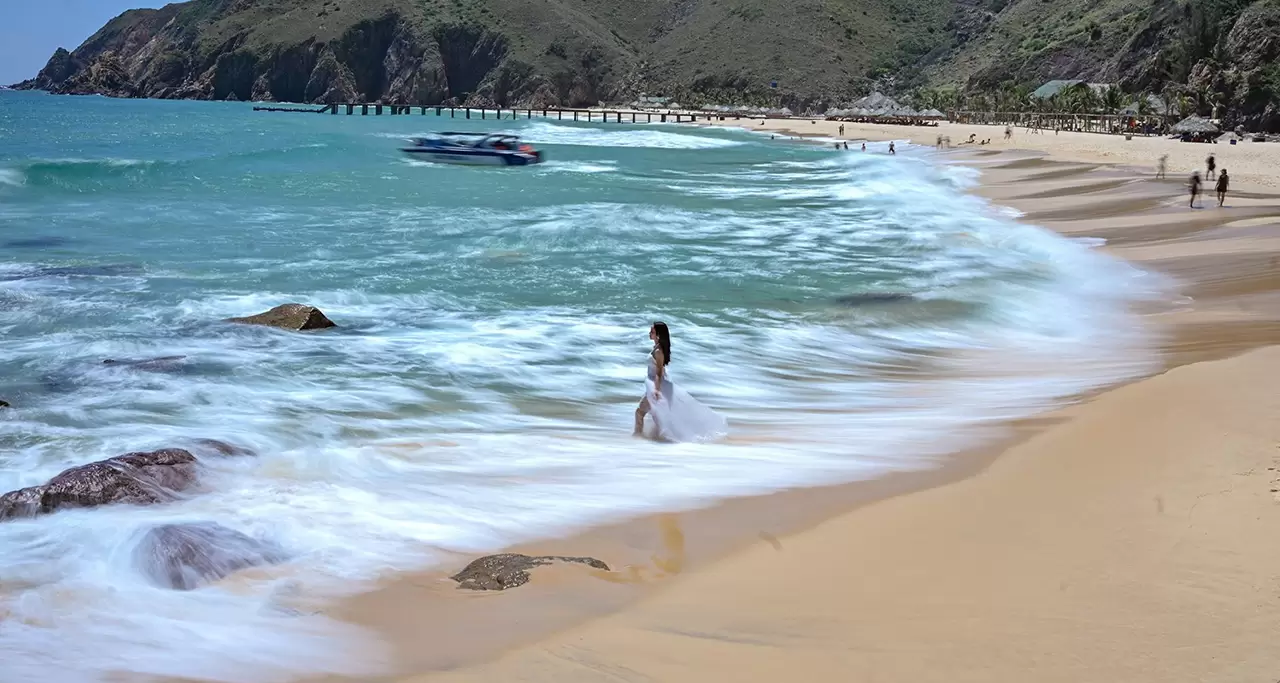 White sand, blue water and foam at the feet of a girl at Quy Nhon, Binh Dinh