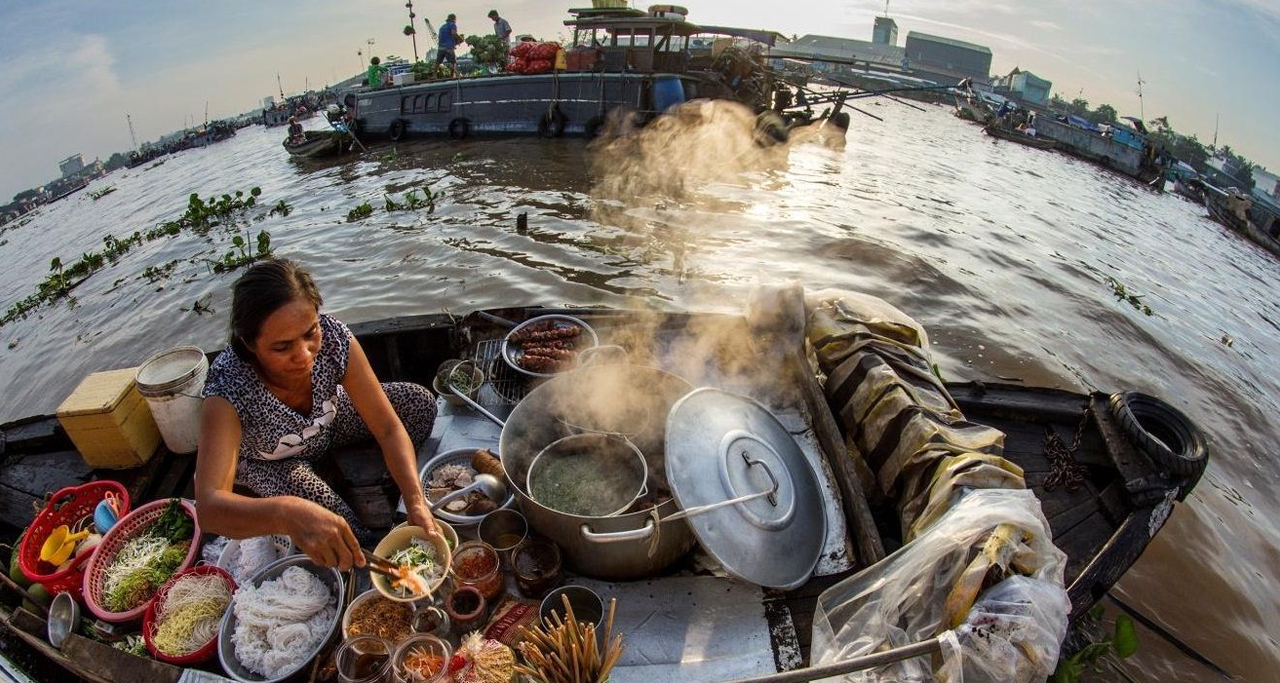 A local serves noodles as breakfast on boat in Cai Rang Floating Market