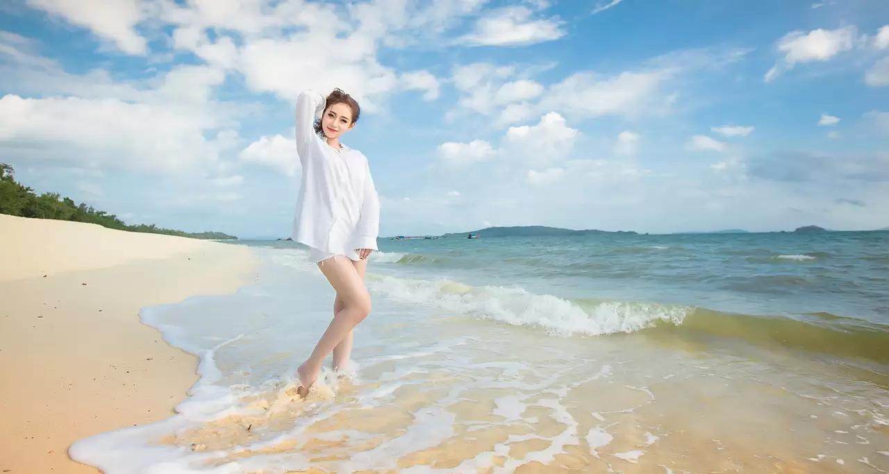 Co To beach with white sand and blue waves is the backdrop for a girl's smile in the photo