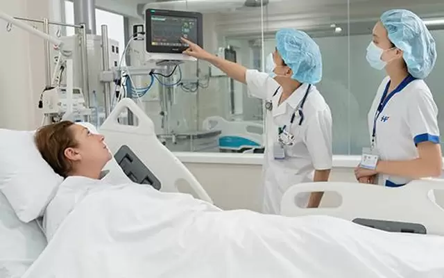 Image of two medical staff taking care of a foreign patient in a recovery room with many modern equipment at a hospital in Vietnam