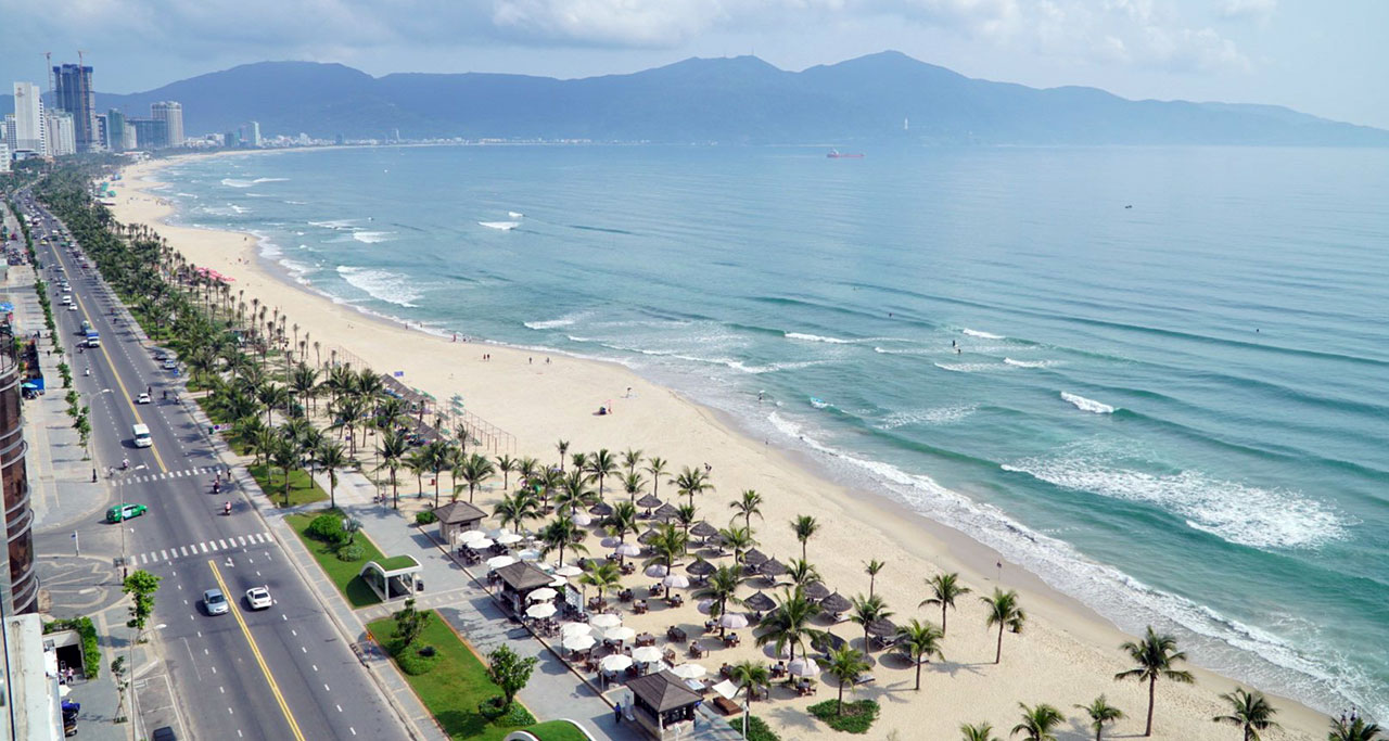 A beach with white sand, blue water and waves at Danang Beach, Da Nang