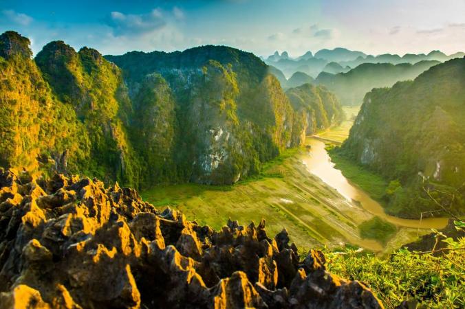 Hikers climbing up the steps to Mua Caves in Ninh Binh, with views of the surrounding mountains in the background. 