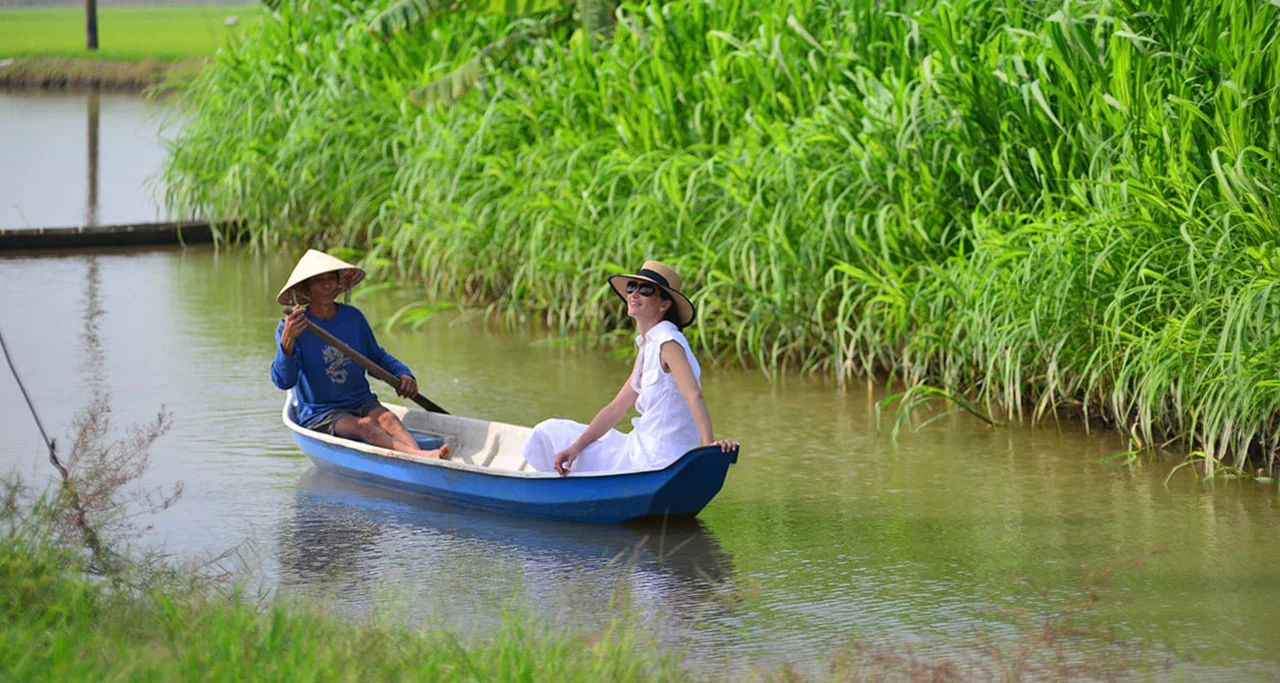 A foreign tourist take a traditional sampan to explore Mekong Delta region