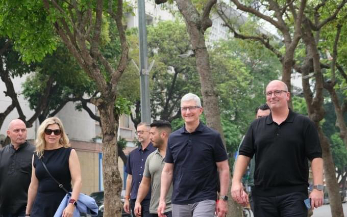 Tim Cook, CEO of Apple, and other Apple executives walking down a narrow street in Hanoi's Old Quarter.