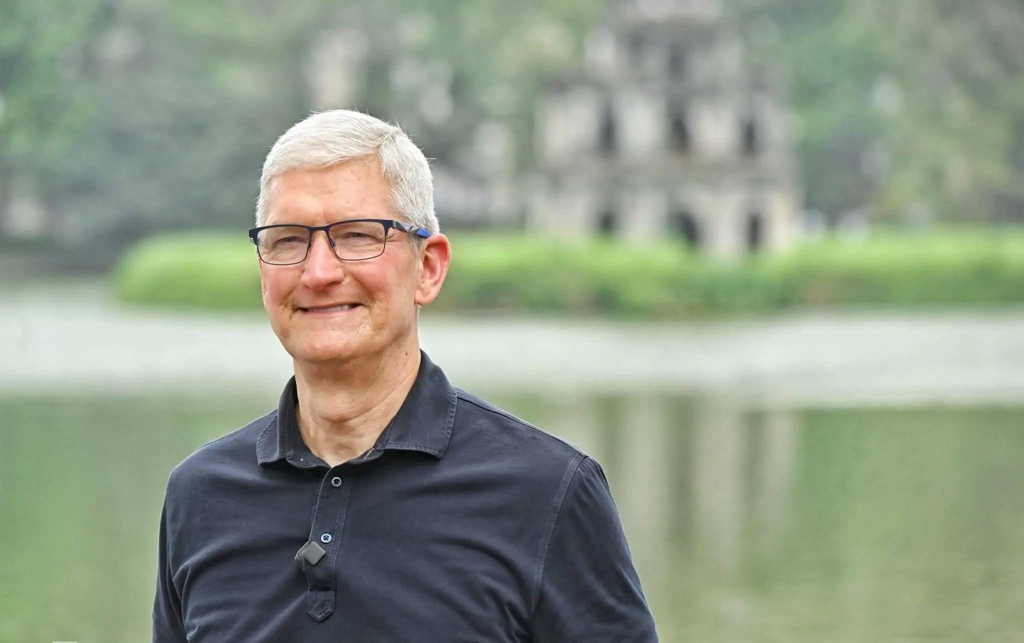 Tim Cook smiles for a photo at Hoan Kiem Lake in Hanoi, Vietnam. The Turtle Tower is visible in the background.