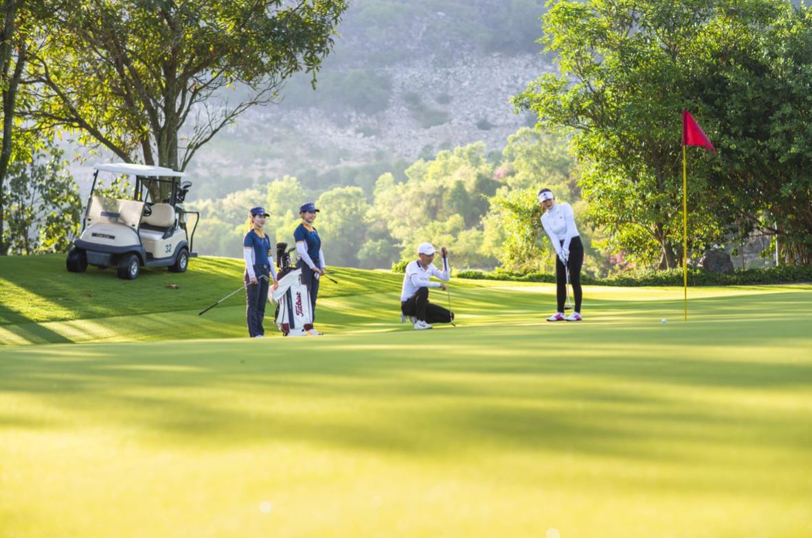 Golfers putting on the green with a shared electric buggy nearby