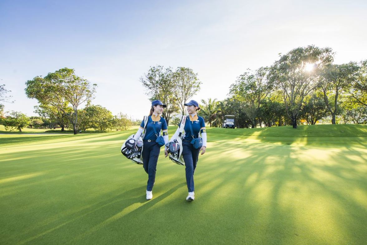 Two caddies walking down the fairway at Vinpearl Golf Nha Trang